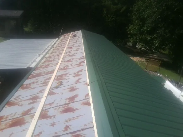 Old rusted panels beside newly installed green metal roofing — Wind Damage Roof Repair by Roofing Brothers in Bernardsville