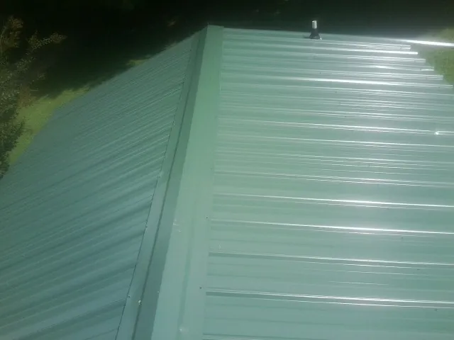 New green metal panels meeting at the ridge of a roof — Flat Roof Repair work by our crew in Bernardsville
