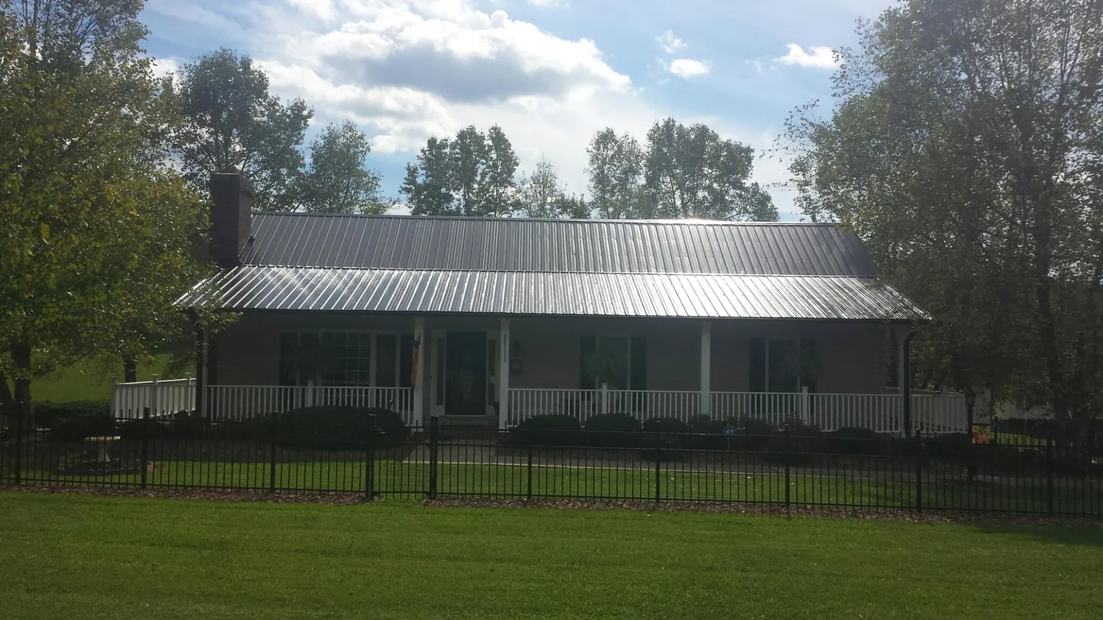 Gray metal roof on a brick ranch with a full width front porch — Gutter Guard Installation work by our crew in Bernardsville
