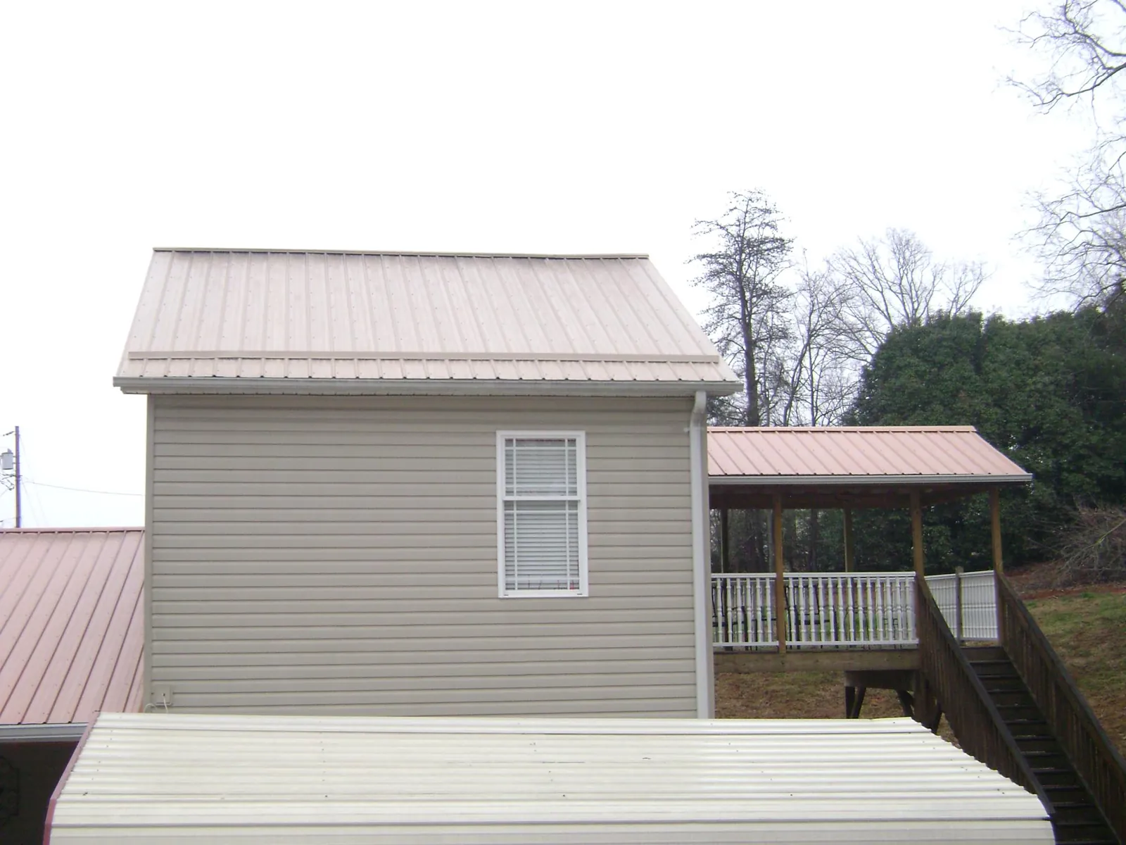 Tan metal roofs on a two story addition and attached porch, from a Roof Replacement job in Bernardsville