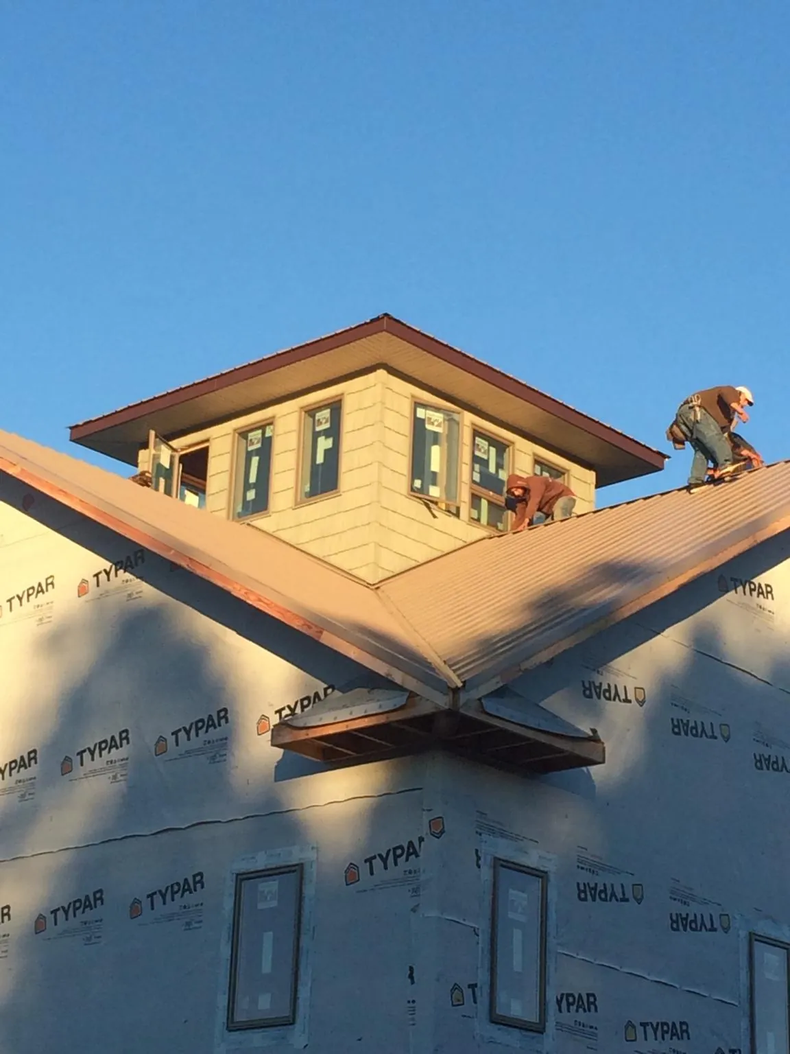Roofers working around a rooftop cupola on a new metal roof at sunset — Roof Waterproofing in Bernardsville by Roofing Brothers